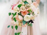 a beautiful peach and cream wedding bouquet with lovely blooms and greenery plus hanging down greenery