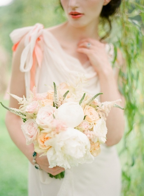 a very delicate peach and cream wedding bouquet with just some greenery looks subtle and chic