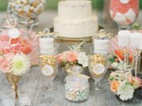 a lovely peach and cream sweets table with coral candies in jars, peachy macarons, peachy and coral blooms and greenery and leaves