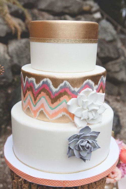 a white and copper wedding cake with a colorful printed tier, gold glitter ribbons and sugar blooms