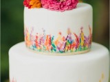 a colorful floral wedding cake with bright frehs blooms on top for a flower child wedding