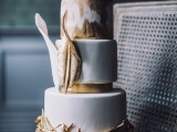 a whimsical gold and white wedding cake with an ikat tier, large gold leaves for decor
