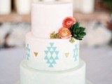 an ombre white to mint wedding cake with geometric patterns and gold leaf plus some fresh blooms and leaves