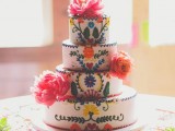 a colorful boho patterned wedding cake with ethnical motifs and bright fresh blooms for decor