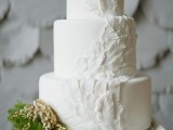 a pure white wedding cake with feather detailing is a unique boho idea done in neutrals