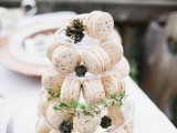 a clear stand with creamy macarons and greenery and pinecones is a lovely idea for a modern wedding, it’s a cool solution to display them at your wedding
