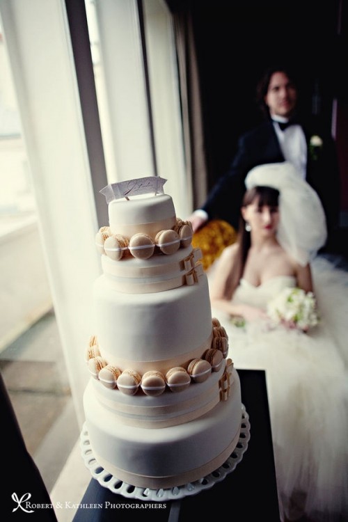 a white buttercream wedding cake decorated with neutral macarons is a creative and interesting idea for a wedding