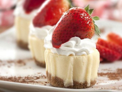 mini cheesecakes with cream on top and some fresh strawberries are delicious