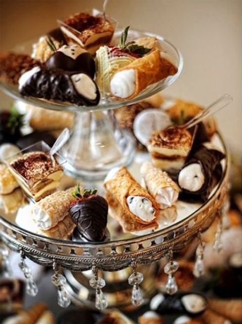 a mirror and crystal stand with mini desserts - chocolate covered strawberries, mini pipes with cream, tiramisu in bowls