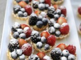 mini tartlets with custard and fresh bluberries, blackberries and raspberries on top and some sugar powder