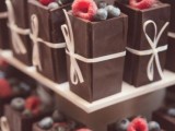 mini chocolate desserts filled with cream and fresh berries on top plus some ties and bows