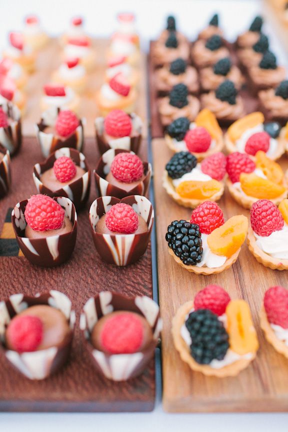 Mini chocolate cups with chocolate cream and fresh raspberries on top and mini tartlets with whipped cream, fresh raspberries and blackberries plus fruit
