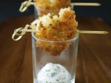 deep fried shrimps on skewers placed on glasses with creamy dip with herbs