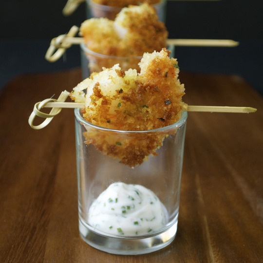 deep fried shrimps on skewers placed on glasses with creamy dip with herbs