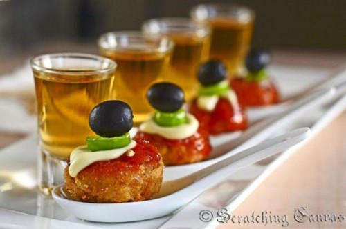 falafels on spoons with ketchup, cream cheese, jalapeno and olives on top