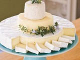 a simple and elegant cheese tower of various kinds of cheese, with greenery and blooms is ideal for any vineyard wedding