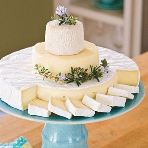 a simple and elegant cheese tower of various kinds of cheese, with greenery and blooms is ideal for any vineyard wedding