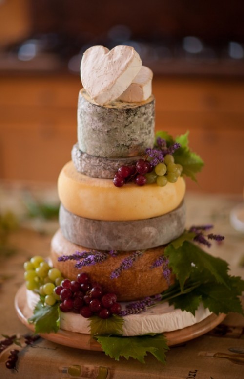 a cheese wheel tower topped with lavender, fresh fruit and berries, with greenery is a fantastic idea for a vineyard wedding