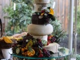 a lush and oversized cheese tower topped with blooms, lots of berries, fruit and greenery is a gorgeous idea for a summer vineyard wedding
