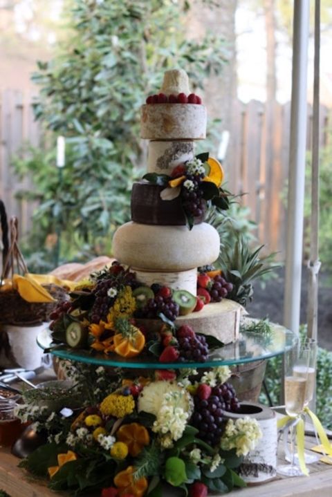 a lush and oversized cheese tower topped with blooms, lots of berries, fruit and greenery is a gorgeous idea for a summer vineyard wedding