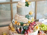 a cheese wheel tower topped with foliage, fresh figs and grapes is a perfect solution for a summer or fall wedding at a vineyard