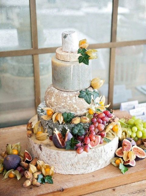 a cheese wheel tower topped with foliage, fresh figs and grapes is a perfect solution for a summer or fall wedding at a vineyard