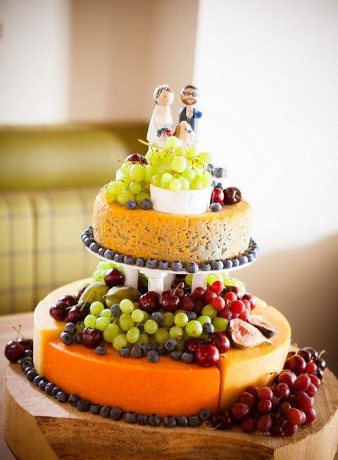 a two-tier cheese wheel tower topped with figs, grapes and fun cake toppers is a lovely idea for a vineyard wedding