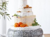 a cheese wheel wedding cake topped with blooms, nuts and fresh tomatoes is a lovely idea for a vineyard wedding