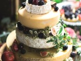 a fantastic cheese wheel wedding tower topped with fresh berries and fruit and with little blooms is amazing