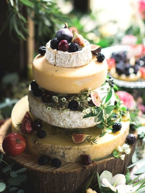 a fantastic cheese wheel wedding tower topped with fresh berries and fruit and with little blooms is amazing