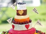 a cheese wheel tower with fresh berries, toppers that mark each tier is a fun and cool alternative to a usual wedding cake
