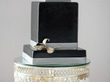 a black square wedding cake with silver ribbons and a touch of metallics