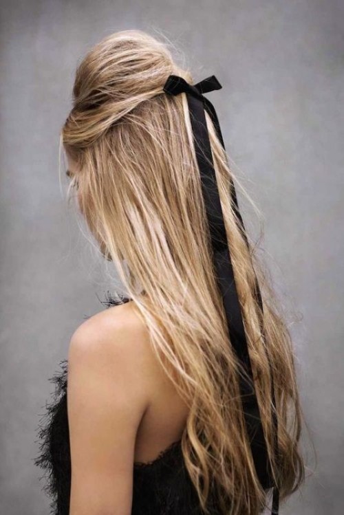 a half updo with a bump accented with a black ribbon bow instead of blooms