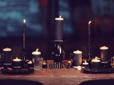 a modern gothic wedding tablescape with black candles, black plates and an uncovered table