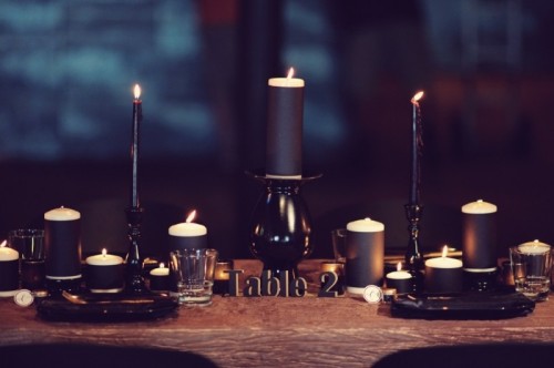 a modern gothic wedding tablescape with black candles, black plates and an uncovered table