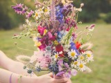 a super colorful boho summer wedding bouquet with pink, fuchsia, blue and red blooms and lots of textural greenery and grasses