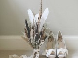 a boho wedding bouquet composed of feathers and baby’s breath with a lace ribbon is a cool idea