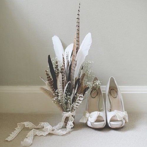 a boho wedding bouquet composed of feathers and baby's breath with a lace ribbon is a cool idea