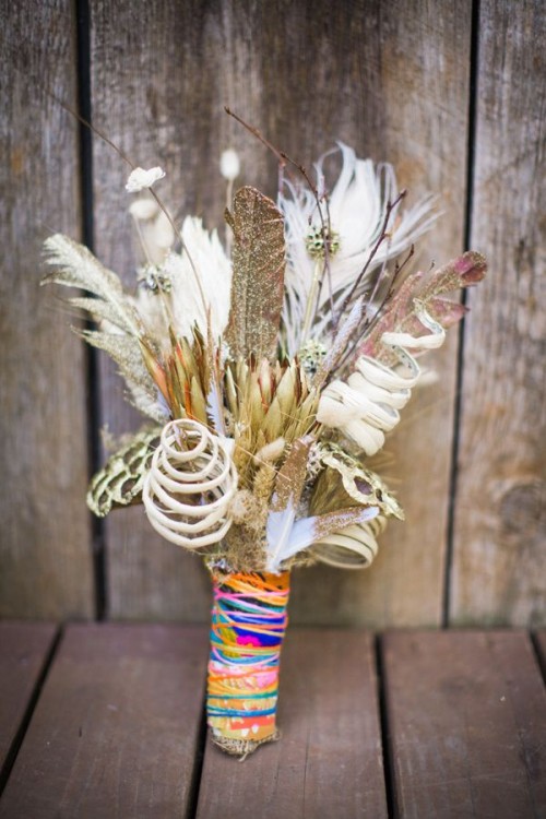 a bright summer wedding bouquet with feathers, curls and a very colorful wrap is a fun idea