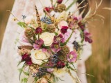 a fall boho wedding bouquet done in white, burgundy, pink, with dried elements, berries and cascading greenery