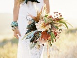 a textural boho wedding bouquet with pastel blooms, greenery, dried leaves and spikes plus feathers for a boho bride