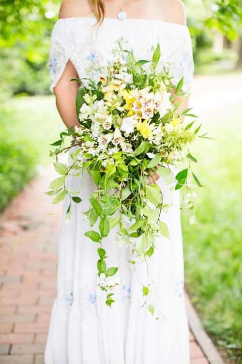 an oversized spring wedding bouquet of blush, yellow blooms and lots of greenery cascading down for a lush and bold boho look
