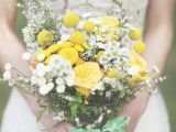 a bright summer boho wedding bouquet of white and yellow blooms, with greenery, billy balls and a simple green wrap