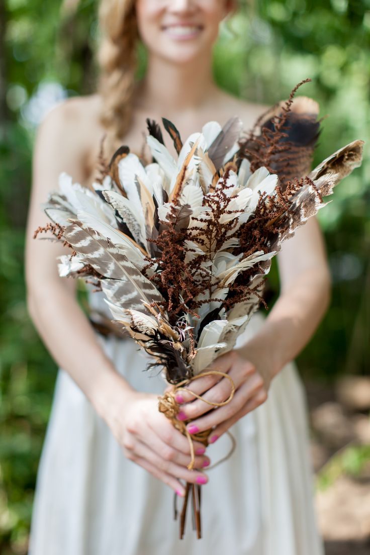 A boho wedding bouquet of feathers and dried elements is a cool idea for a fall boho bride