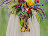a colorful wedding bouquet of orange, yellow, blue, purple and other flowers plus various spikes and textural elements here and there