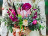 a bright wedding bouquet of pink and fuchsia blooms, thistles, feathers, spikes and lots of greenery to rock for a summer boho bride