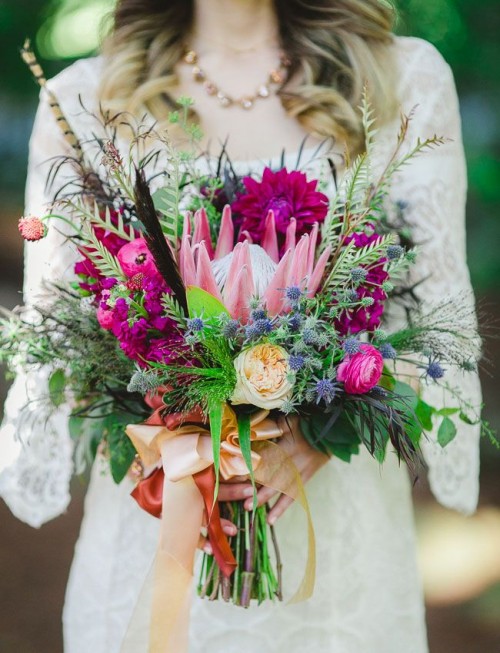 a bright wedding bouquet of pink and fuchsia blooms, thistles, feathers, spikes and lots of greenery to rock for a summer boho bride
