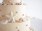 a tan textural wedding cake with pearls, seashells and starfish is a stylish wedding cake idea to try