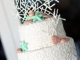 a white textural wedding cake with red seashells and green starfish plus a creative sugar topper for a beach wedding