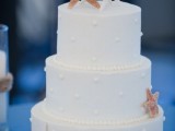 an elegant white wedding cake with dots, starfish of sugar for a stylish all-white beach wedding